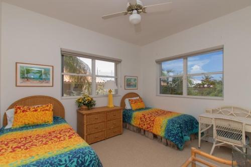 a bedroom with two beds and two windows at Pelican Landing in Islamorada