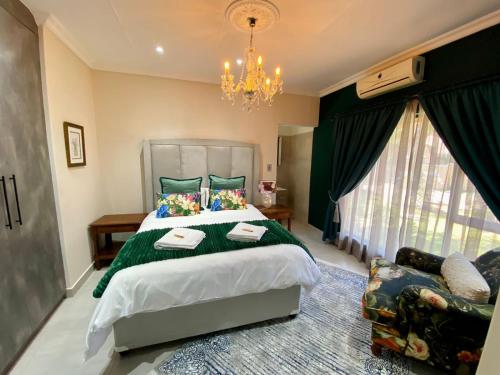 a bedroom with a large bed and a chandelier at Blissful Bracelet in Nelspruit