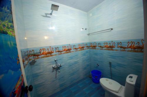 a bathroom with a toilet and a mural on the wall at MARARI GOD's OWN VILLA in Alleppey