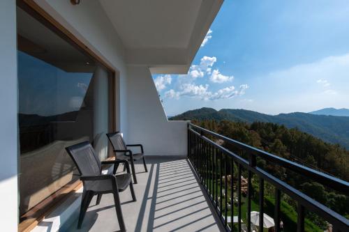 a balcony with two chairs and a view of the mountains at Ekant Retreat Resort in Chail