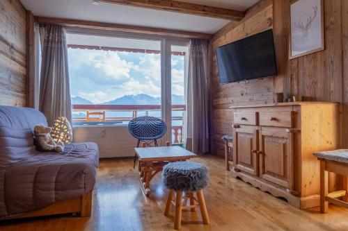 un salon avec un canapé et une grande fenêtre dans l'établissement Appartement Barco - Welkeys, à Huez