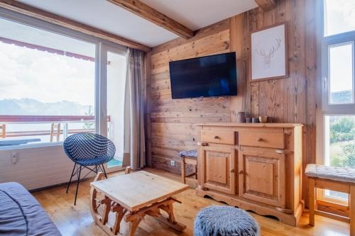 - un salon avec une télévision et un mur en bois dans l'établissement Appartement Barco - Welkeys, à Huez