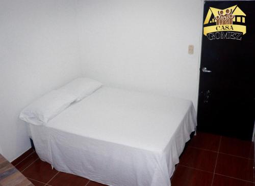 a small bedroom with a white bed and a black door at Casa Gomez Apto 2 in Leticia