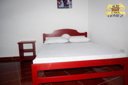 Cama en habitación con marco de cama rojo y mesita de noche en Casa Gomez Apto 2, en Leticia