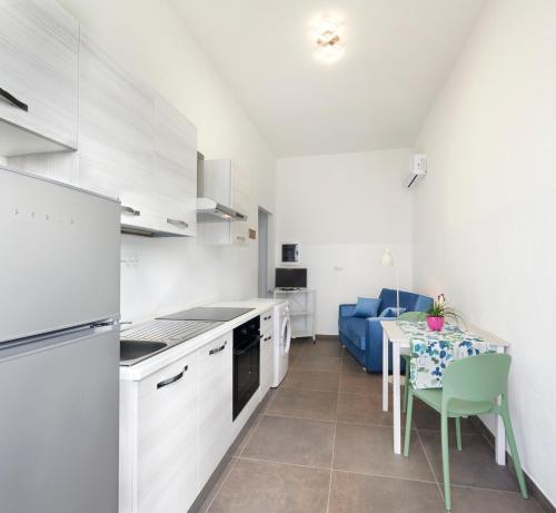 a white kitchen with a table and a blue couch at Casa Cicolani in Scardovari