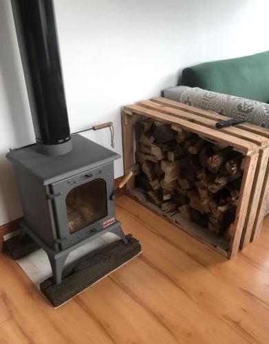 una estufa de leña en la sala de estar con una pila de madera en El Rejunte en Miramar