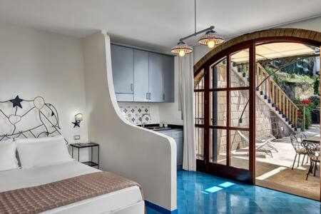 een slaapkamer met een bed en een keuken met een trap bij Vera ed il Vervece by Gocce On the Sea in Massa Lubrense