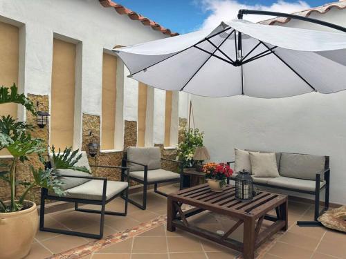 Casa Oasis - Centro histórico ( Pocos pasos de la plaza principal) في فيلا دي ليفا: فناء فيه كراسي ومظلة وطاولة