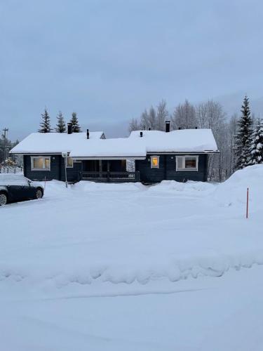 a house with a snow covered roof in a parking lot at Yllästölli 2 D, Äkäslompolo in Kolari