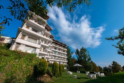 a tall white building with chairs and an umbrella at Ekant Retreat Resort in Chail