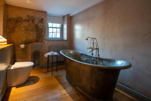 a bathroom with a copper tub and a toilet at The Archangel,Restaurant & Bar with Rooms in Frome