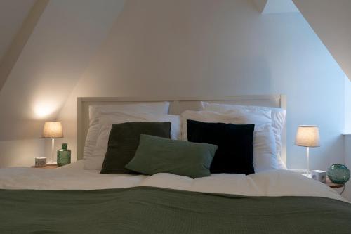 - un lit blanc avec des oreillers verts et noirs dans l'établissement Charmante Maisonette im Schnoor, à Brême