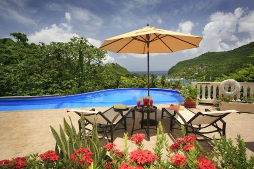 a table and chairs with an umbrella next to a swimming pool at Beautiful 5-Bedroom Villa Ashiana in Marigot Bay villa in Marigot Bay