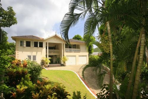 a white house with a driveway and palm trees at Beautiful 5-Bedroom Villa Ashiana in Marigot Bay villa in Marigot Bay