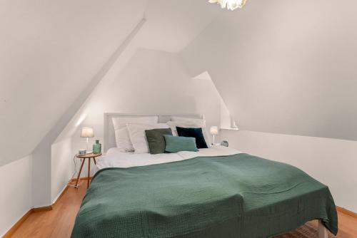 een witte slaapkamer met een bed met groene lakens en kussens bij Charmante Maisonette im Schnoor in Bremen