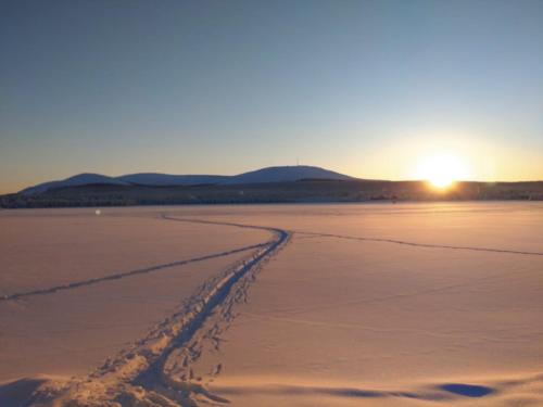 a track in the sand on a beach at sunset at Yllästölli 2 D, Äkäslompolo in Kolari