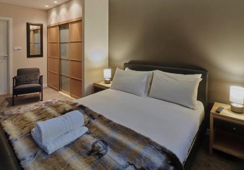 a bedroom with a large bed and a chair at Glasgow, Finnieston Luxury 2 Bed with parking, e-check in, hi-fi in Glasgow