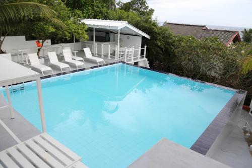 a large blue swimming pool with white chairs around it at Talalla Leisure in Talalla
