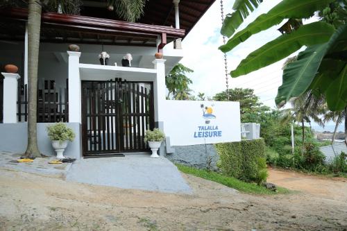 a sign in front of a house with a gate at Talalla Leisure in Talalla