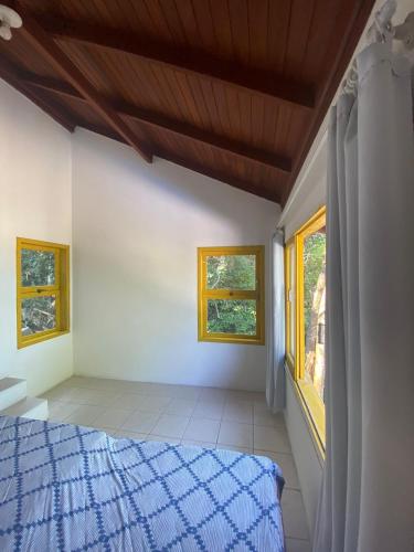 um quarto com uma cama e duas janelas em Casa Sambaqui beira mar em Florianópolis