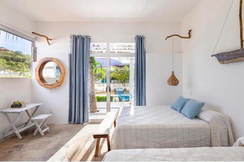 a bedroom with a bed and a table and a window at La Bocana Surf House in Santa Cruz Huatulco