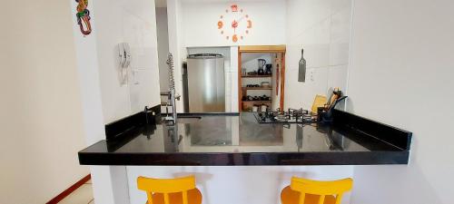 uma cozinha com um balcão e dois bancos amarelos em COPDS0103 - Condomínio Aldeiotta em Salvador