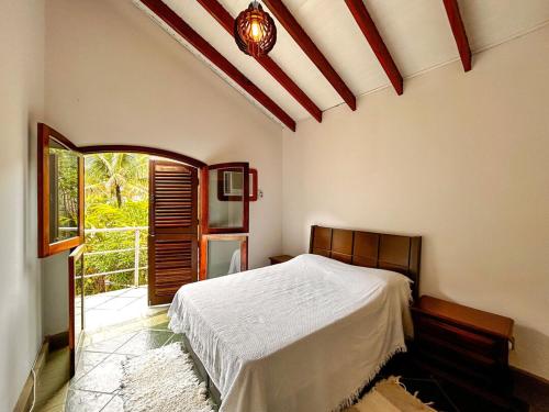 um quarto com uma cama e uma grande janela em Casa a 180m da Praia do Toque Toque Pequeno SP em São Sebastião