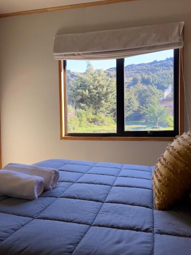 a bedroom with a blue bed and a window at Siempre Verde in Puerto Tranquilo