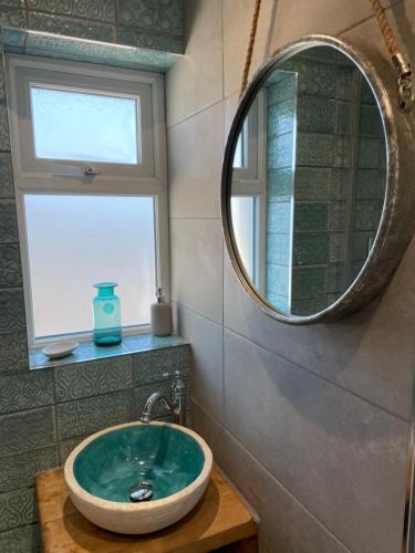 W łazience znajduje się umywalka i lustro. w obiekcie 2 Fernleigh Villas w mieście Perranporth