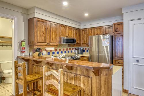 Una cocina con gabinetes de madera y un refrigerador de acero inoxidable. en 124 Algonquin - Ski In Out Tremblant Mountainside Chalet, en Mont-Tremblant
