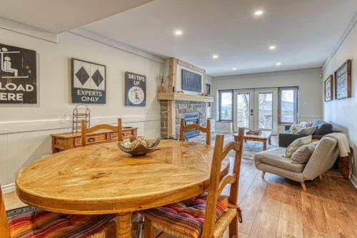 cocina y sala de estar con mesa de madera y sillas en 124 Algonquin - Ski In Out Tremblant Mountainside Chalet, en Mont-Tremblant