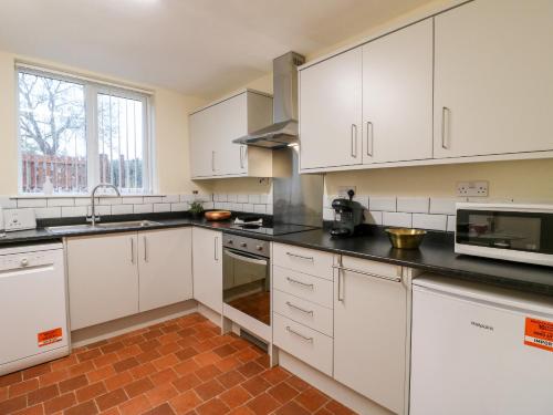 a kitchen with white cabinets and black counter tops at 8 Church Lane in Checkley