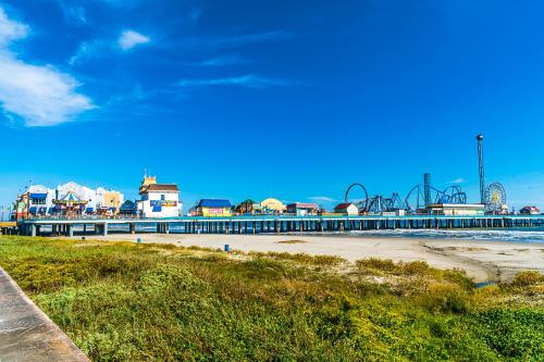 einen Strand mit einem Pier mit Achterbahn in der Unterkunft Relax in the Heart of Galveston in Galveston