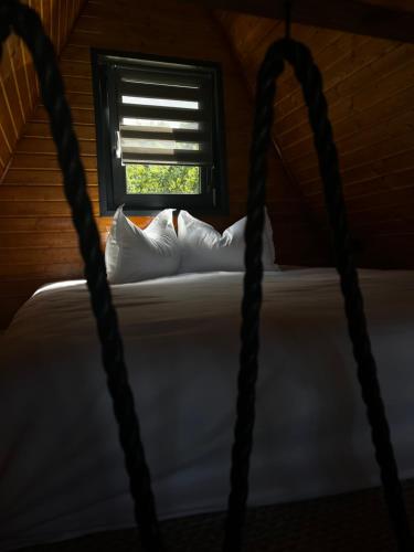 a bed with white pillows in a room with a window at Rock Valley Cabins A-frame in Ibăneşti