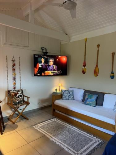 a room with a bed with a tv on the wall at Chalés Camburi in São Sebastião