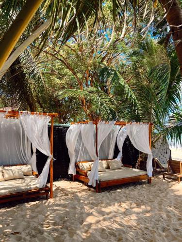 two beds under a palm tree on the beach at Pousada Minha Praia in João Pessoa