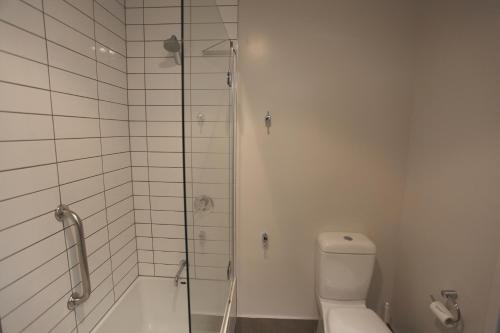 a white bathroom with a shower and a toilet at Hotel Ashburton in Ashburton
