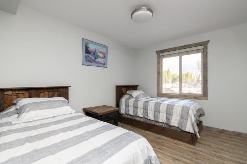 sypialnia z 2 łóżkami i oknem w obiekcie The Antler Ridge Cabin w mieście Valemount
