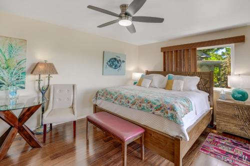 1 dormitorio con 1 cama con ventilador de techo y mesa en Marjorie's Kauai Inn, en Lawai