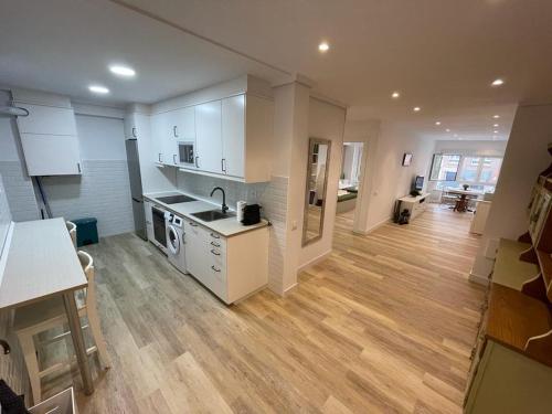 a kitchen with white cabinets and a wooden floor at Villa Sidra Gascona in Oviedo