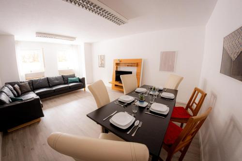 a living room with a dining table and a living room with a couch at Yello Homes - großes Apartment - Am Waldrand, 15 min bis Nürnberg Messe, für 8 Personen, 2 WC's in Schwarzenbruck