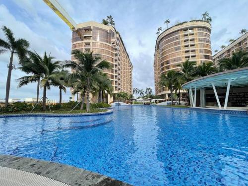 a large swimming pool with palm trees and buildings at Orkide Condo By 365Home in Phnom Penh