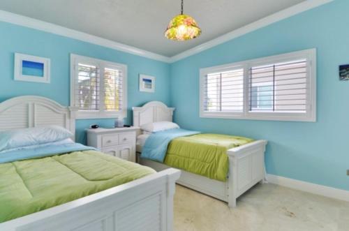 a blue bedroom with two beds and a chandelier at West Plaza Del Lago in Islamorada