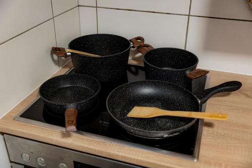 a frying pan on a stove with two pots at Yello Homes - großes Apartment - Am Waldrand, 15 min bis Nürnberg Messe, für 8 Personen, 2 WC's in Schwarzenbruck