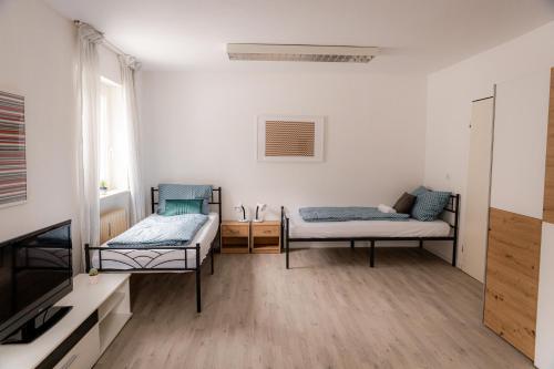 a room with two beds and a television in it at Yello Homes - großes Apartment - Am Waldrand, 15 min bis Nürnberg Messe, für 8 Personen, 2 WC's in Schwarzenbruck