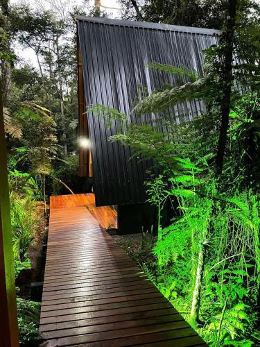 a wooden walkway leading to a house in a forest at Deck1920 by Estadias Incríveis in Cascavel