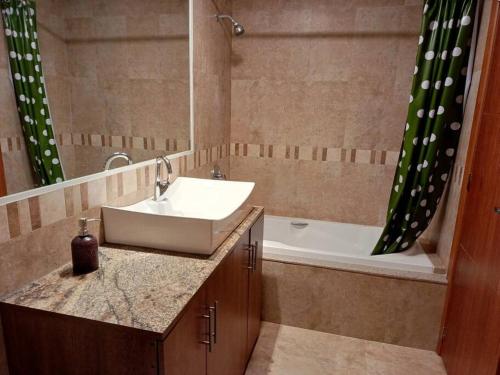 a bathroom with a sink and a bath tub with a mirror at Depar Rio Cuenca - Confortable in Cuenca
