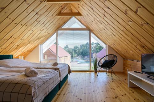 a bedroom with a bed and a large window at Domki Mewa in Jantar