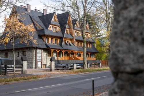 a large house with a gambrel roof on a street at Dom Wczasowy Grań in Zakopane