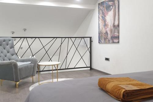 ein Schlafzimmer mit einem Bett, einem Stuhl und einer Decke in der Unterkunft R-RESIDENCY DELUXE in Banja Luka